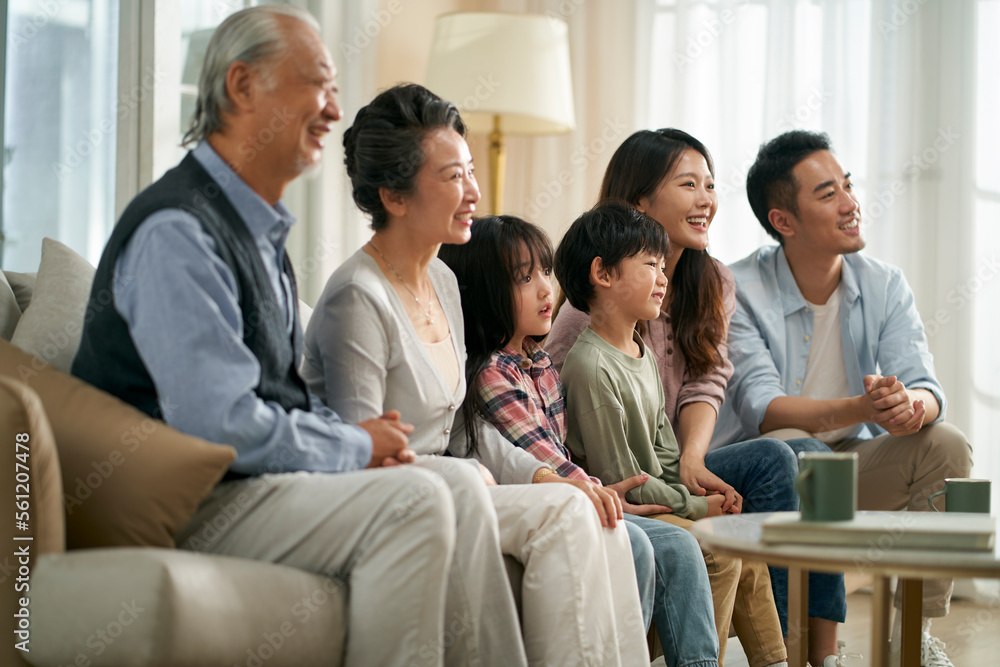 three generation asian family watching tv together at home three generation asian family watching tv together at home