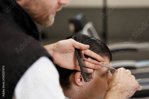 hairdresser does haircut for caucasian bearded man