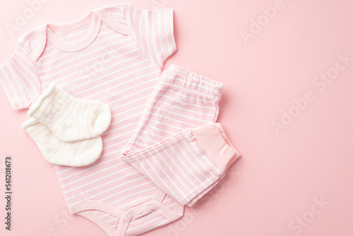 Infant clothes concept. Top view photo of pink bodysuit pants and socks on isolated pastel pink background with empty space © ActionGP