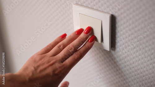 Fotografie Closeup of woman hand is turned off on light switch at home
