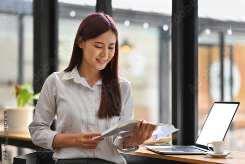 Young Asian woman in smart casual reading a book while sitting on the counter bar with Empty of screen laptop. Free Download Young Asian woman in smart casual reading a book while sitting on the counter bar with Empty of screen laptop. - GFXLoad