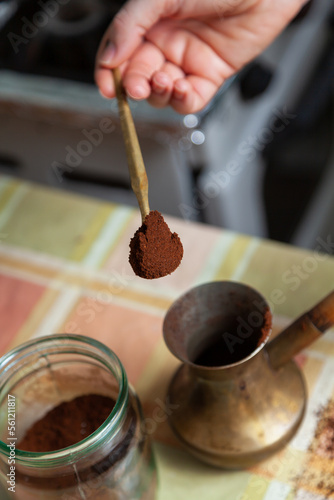 Hand pouring ground coffee into cezve close-up..