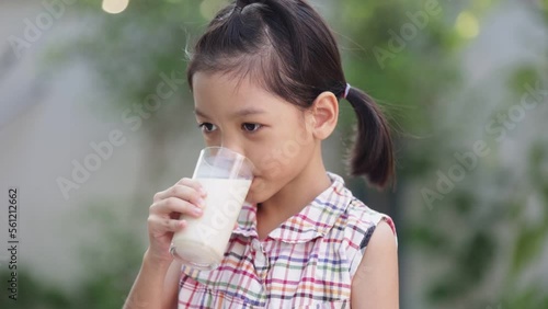 Portrait of a cute Thai Asian girl aged 6 to 8 years old holding a glass of milk. She was happily drinking milk and smiling. and thumbs up like She likes to drink milk because it strengthens her body. photo