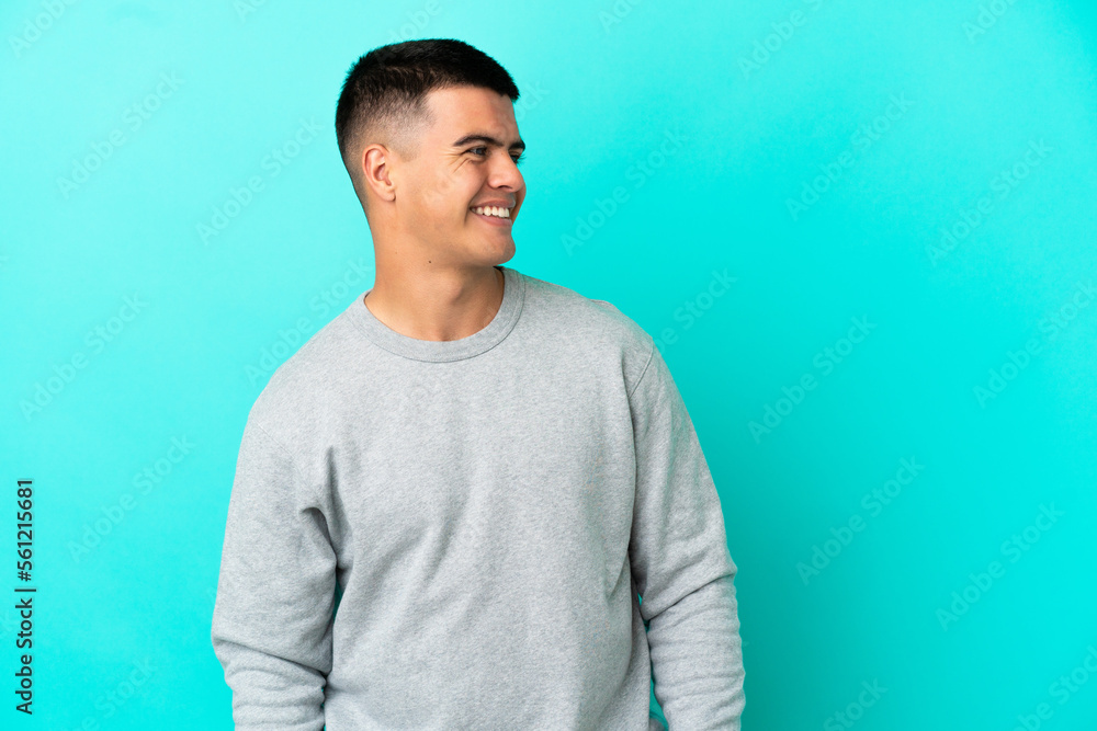 Young handsome man over isolated blue background looking to the side and smiling Young handsome man over isolated blue background looking to the side and smiling