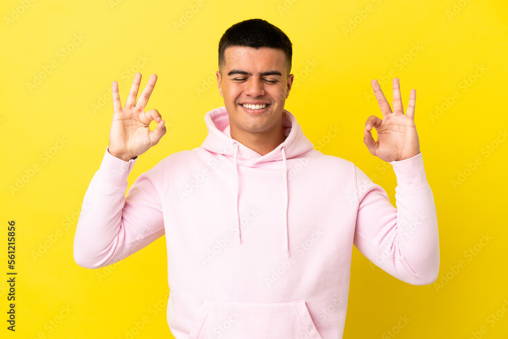 Young handsome man over isolated yellow background in zen pose Young handsome man over isolated yellow background in zen pose