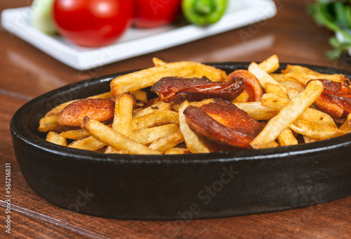 Frying pan with pieces fried sausage and potato