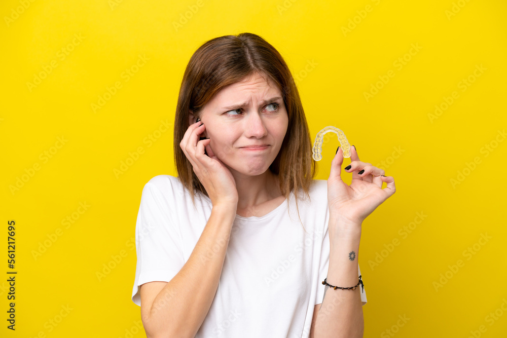 Young English woman holding invisible braces frustrated and covering ears Young English woman holding invisible braces frustrated and covering ears