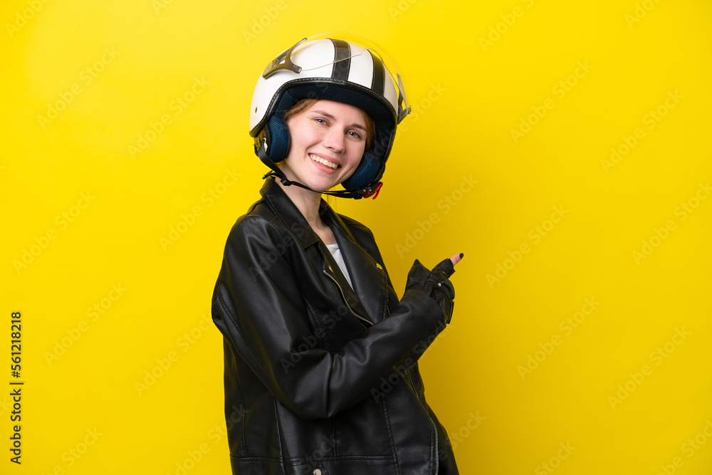 Young English woman with a motorcycle helmet isolated on yellow background pointing back Young English woman with a motorcycle helmet isolated on yellow background pointing back