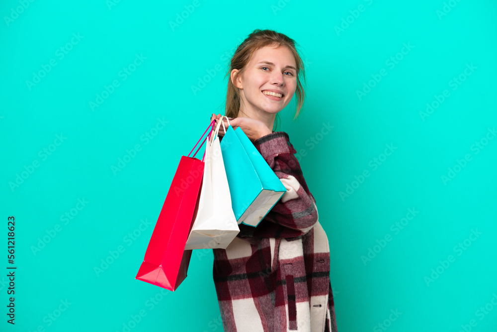 Young English woman isolated on blue background holding shopping bags and smiling Young English woman isolated on blue background holding shopping bags and smiling