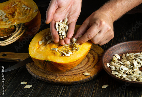 Hands of a person or chef takes out the seeds from the pumpkin for use in cooking. Peasant food.