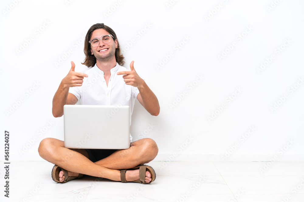 Young handsome man with a laptop sitting on the floor isolated on white background proud and self-satisfied Young handsome man with a laptop sitting on the floor isolated on white background proud and self-satisfied