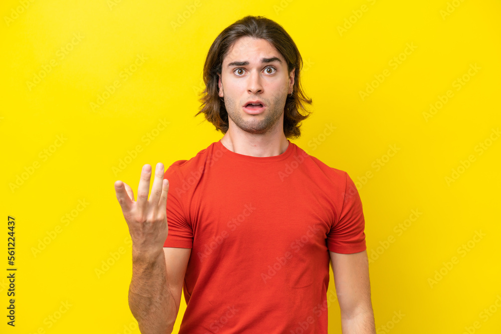 Caucasian handsome man isolated on yellow background making doubts gesture Caucasian handsome man isolated on yellow background making doubts gesture