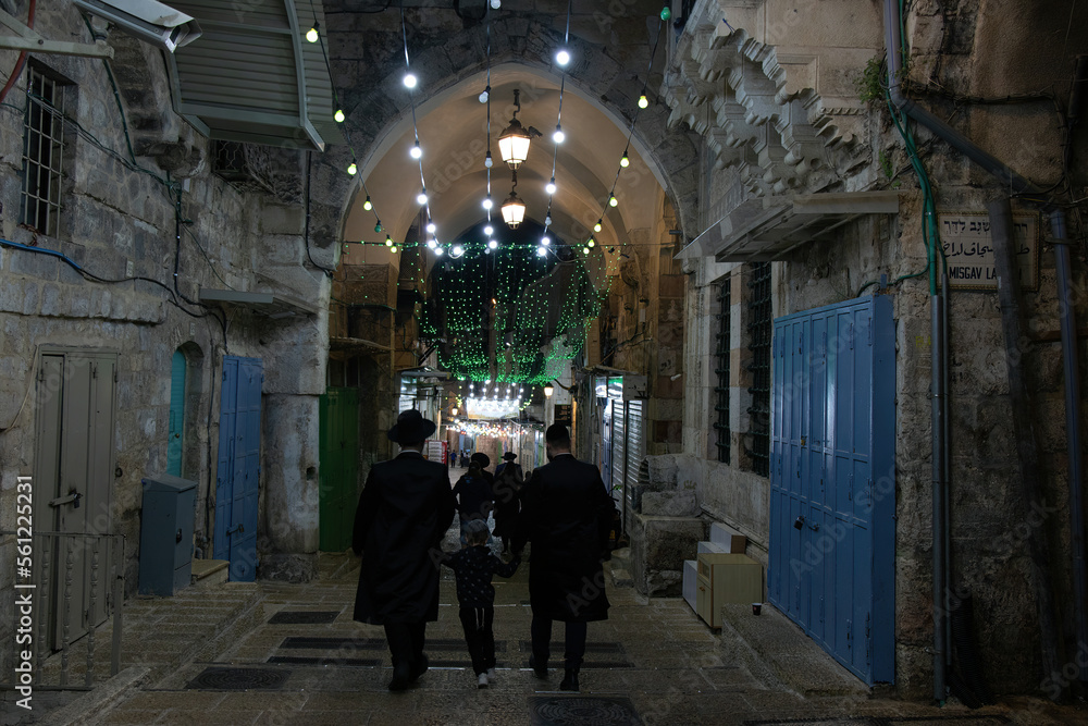 Night view of ancient street in the old city of Jerusalem - Israel: 21 April 2022. Jewish families walking on the street of old city.