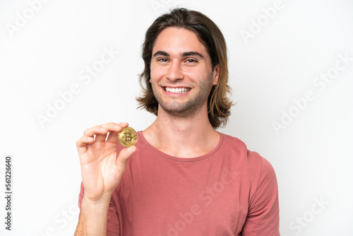 Young handsome man holding a Bitcoin isolated on white background smiling a lot © luismolinero