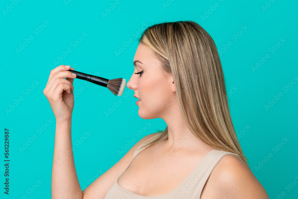 Young caucasian woman isolated on blue background holding makeup brush Young caucasian woman isolated on blue background holding makeup brush