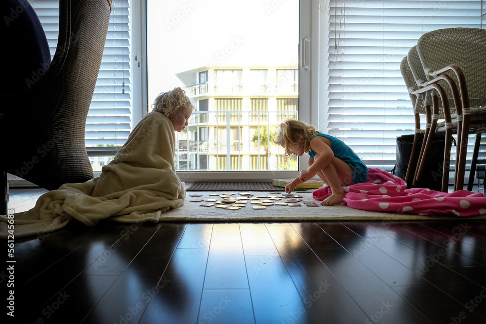 little girls play card game sitting on rug cuddling in blankets little girls play card game sitting on rug cuddling in blankets