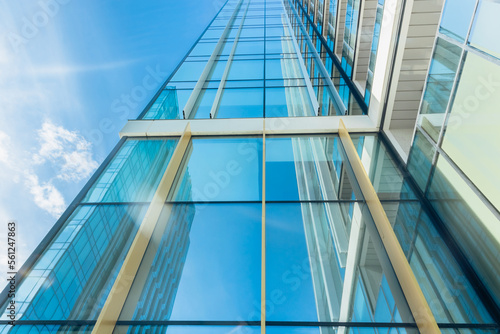 The blue sky is reflected in the windows of a modern office building. Architecture and exterior of contemporary houses