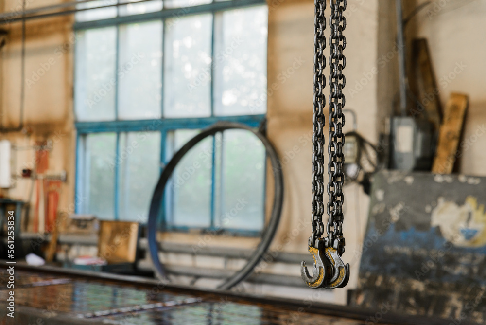 Production crane equipment, metal hooks hanging on chains in the production hall.