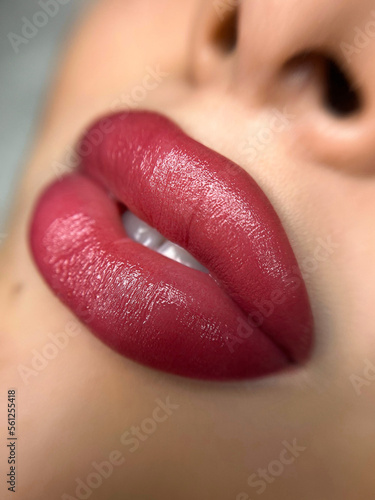 permanent makeup on the lips of a young woman of a delicate peach shade close-up, a girl after a cosmetic procedure with smooth and clean healthy skin.