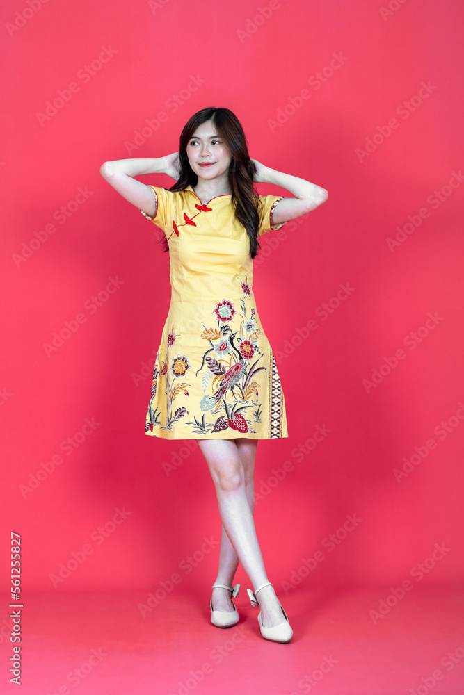 A beautiful asian woman doing a pose while wearing simple yellow chinese dress A beautiful asian woman doing a pose while wearing simple yellow chinese dress