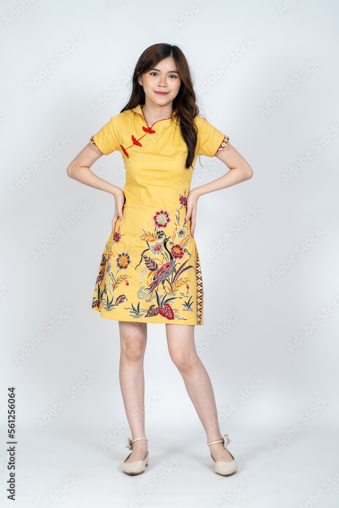 A beautiful asian woman doing a pose while wearing simple yellow chinese dress A beautiful asian woman doing a pose while wearing simple yellow chinese dress