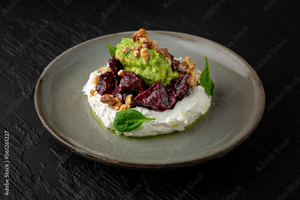 Dried beets with young cheese and guacamole in a ceramic plate on a dark textured background. Restaurant menu Isolated on black Dried beets with young cheese and guacamole in a ceramic plate on a dark textured background. Restaurant menu Isolated on black