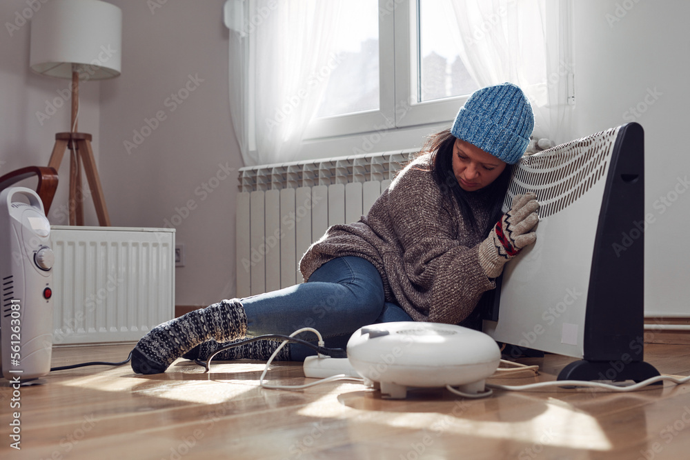 Woman in jacket, sweater and hand gloves indoors on a chilly winter day, energy and gas crisis, cold room, heating problems. Woman in jacket, sweater and hand gloves indoors on a chilly winter day, energy and gas crisis, cold room, heating problems.