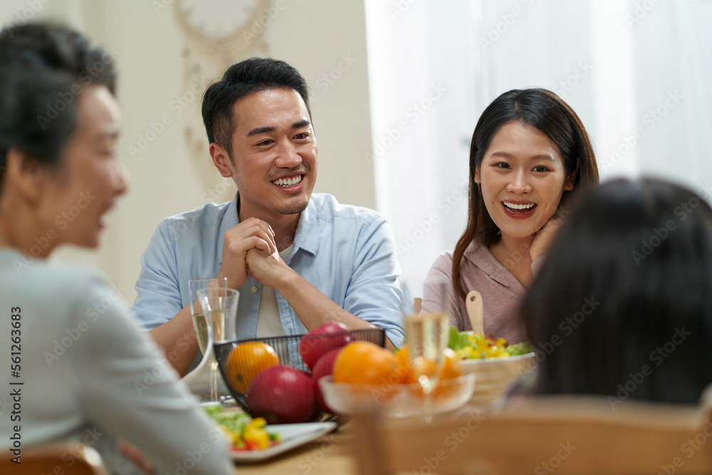 happy asian family chatting while eating meal at home