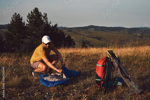 Man camping in nature  unpacking and packing small tent outdoors  recreation and hobbies.