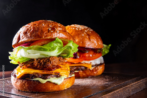 two barbecue pulled beef burgers with vegetables on dark background