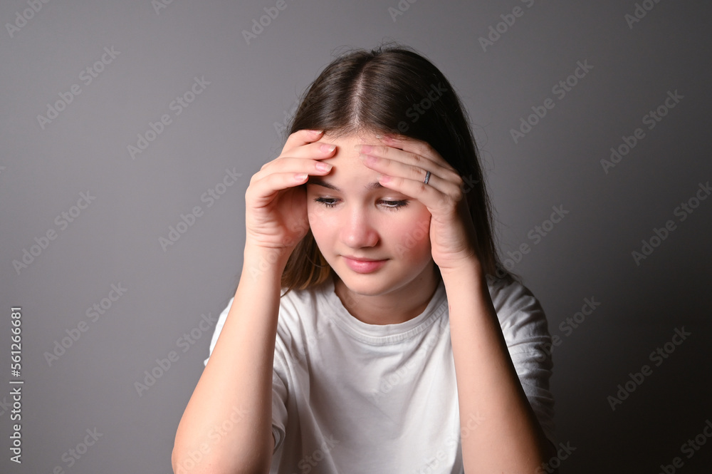 Portrait of sad teen girl on gray background. Teenage girl looking thoughtful about troubles Portrait of sad teen girl on gray background. Teenage girl looking thoughtful about troubles