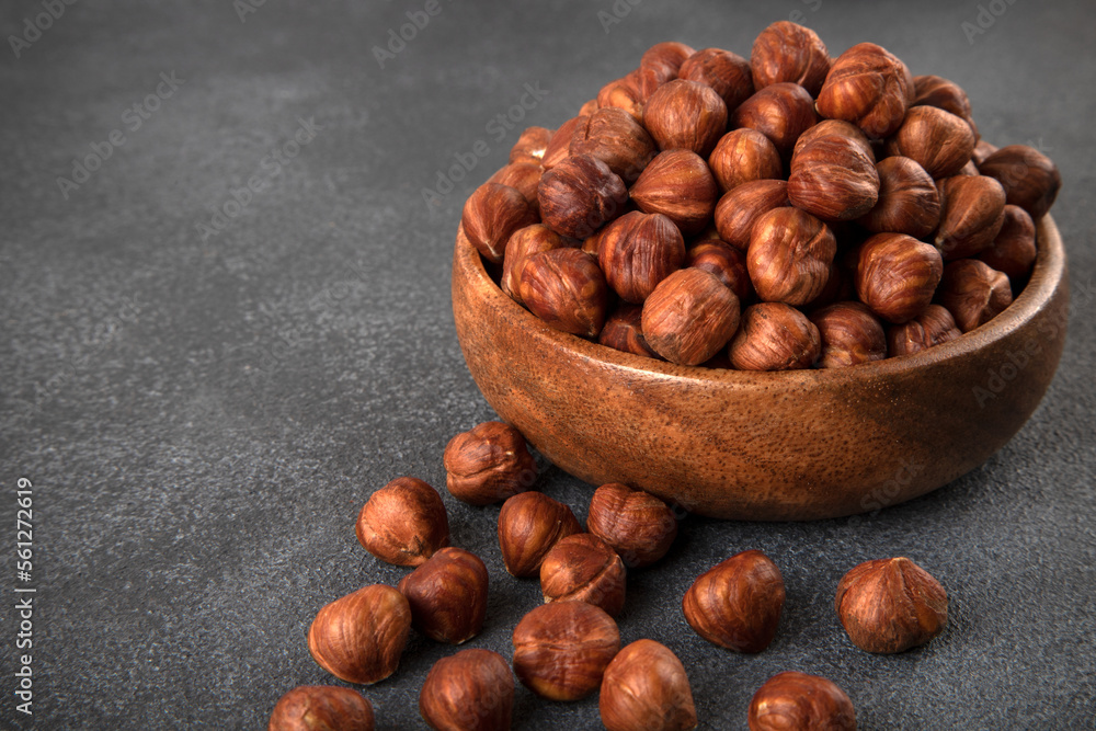 View of a bowl full of hazelnuts on a dark background View of a bowl full of hazelnuts on a dark background