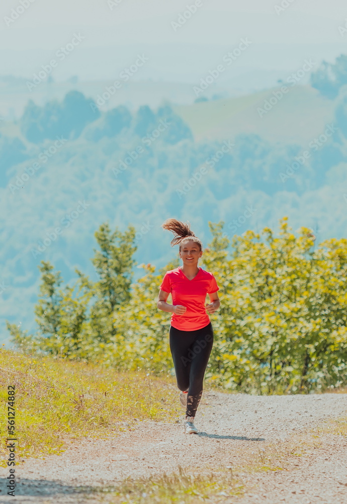 Young happy woman enjoying in a healthy lifestyle while jogging on a country road through the beautiful sunny forest, exercise and fitness concept Young happy woman enjoying in a healthy lifestyle while jogging on a country road through the beautiful sunny forest, exercise and fitness concept