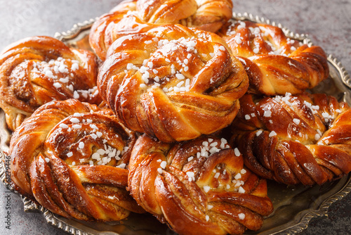 Fotografia Swedish cinnamon rolls kanelbullar topped with pearl sugar close-up on a plate on the table