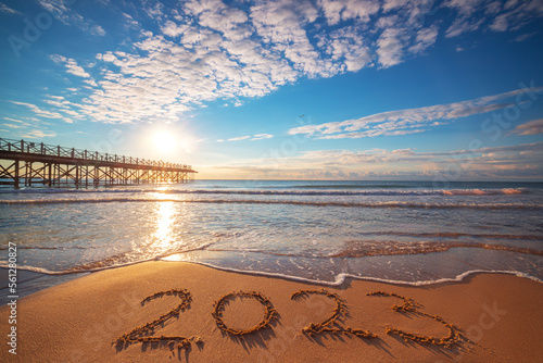 Fototapeta Naklejka Na Ścianę i Meble -  New Year 2023 beach sunrise. Text 2023 in sea sand, nature ocean landscape
