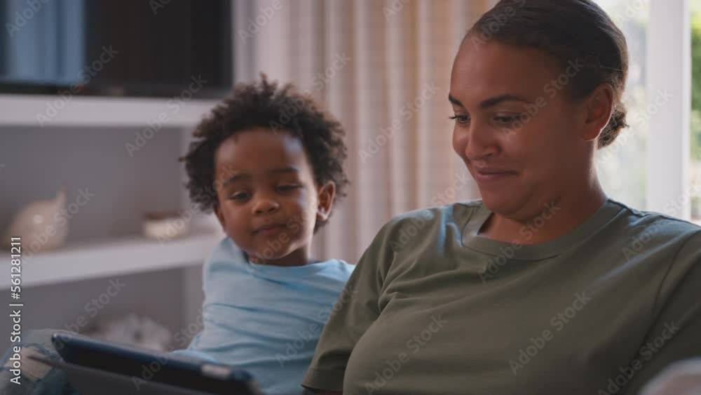 Mother With Son Playing Game Or Streaming To Digital Tablet Sitting On Sofa At Home Together Mother With Son Playing Game Or Streaming To Digital Tablet Sitting On Sofa At Home Together