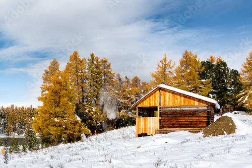 Wooden hut in autumn mountain forest. Season of change from autumn to winter.