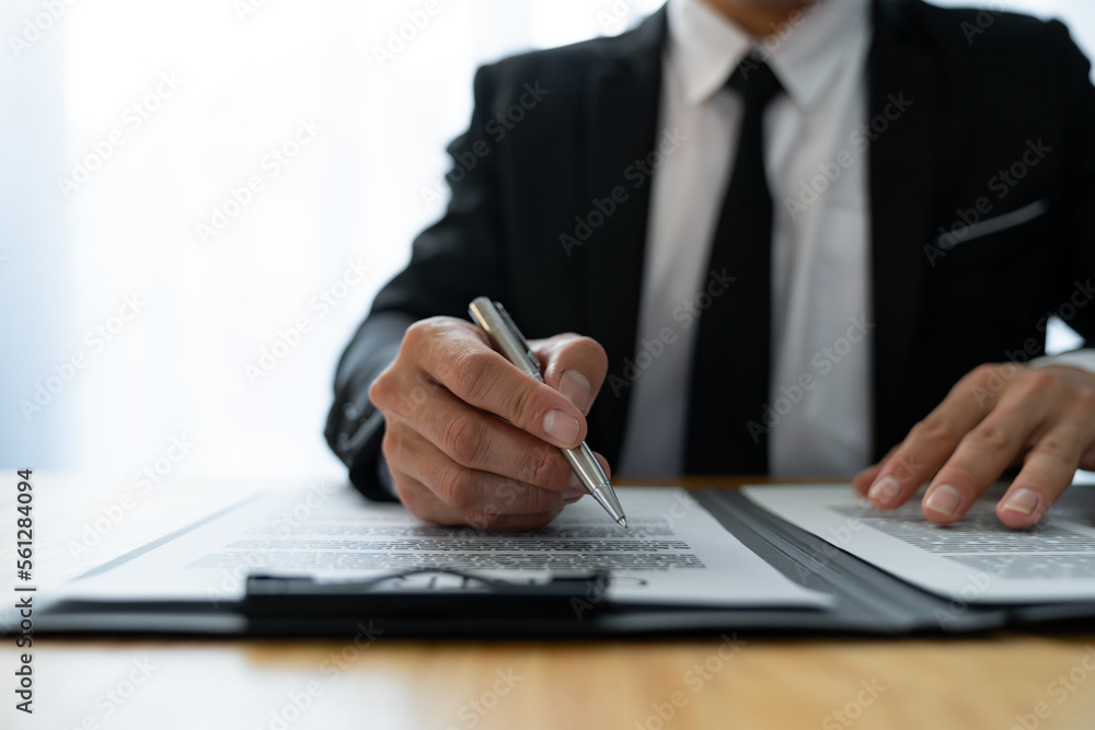 Young Asian legal advisor or lawyer reading financial details investment agreement Signing a contract for validity before the delivery of documents to help his clients succeed. Young Asian legal advisor or lawyer reading financial details investment agreement Signing a contract for validity before the delivery of documents to help his clients succeed.
