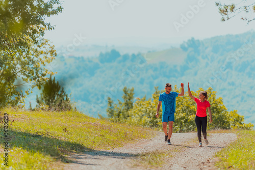 Couple enjoying in a healthy lifestyle while jogging on a country road through the beautiful sunny forest, exercise and fitness concept © .shock
