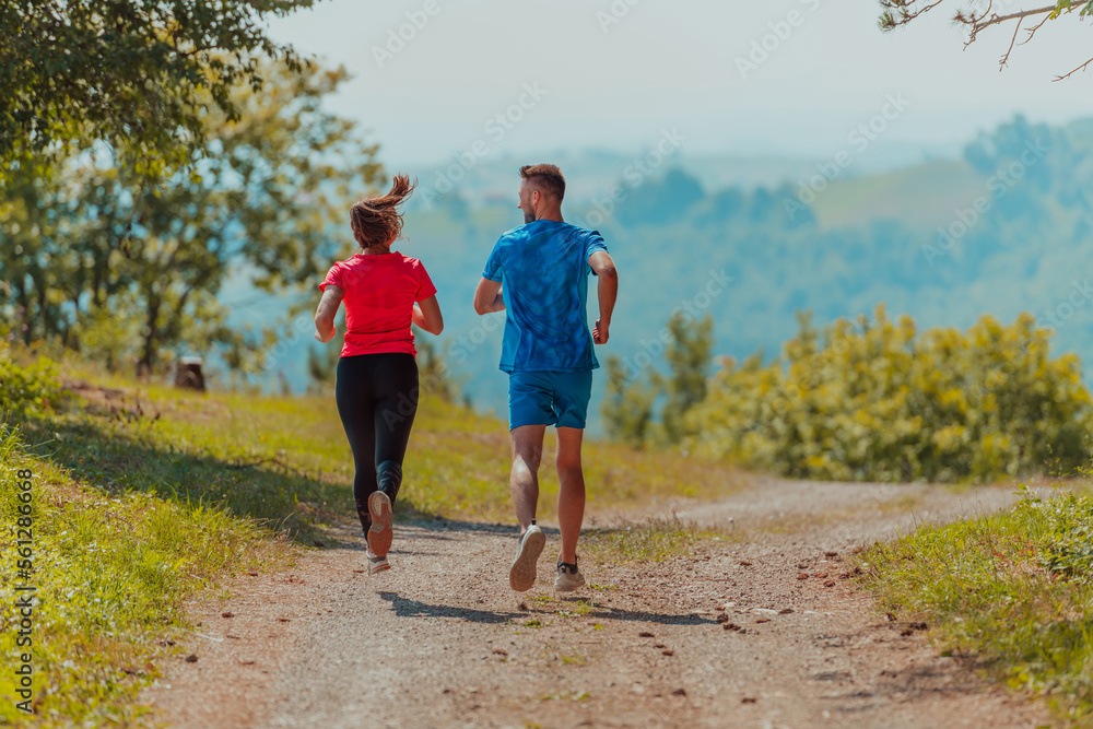 Couple enjoying in a healthy lifestyle while jogging on a country road through the beautiful sunny forest, exercise and fitness concept Couple enjoying in a healthy lifestyle while jogging on a country road through the beautiful sunny forest, exercise and fitness concept