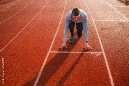 Young athlete in position on the starting blocks on a track. Runner ready for the start, symbol of preparation and success 