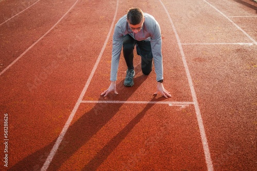 Young athlete in position on the starting blocks on a track. Runner ready for the start, symbol of preparation and success 