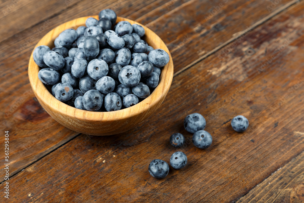Freshly picked blueberries in wooden bowl on wooden background. Concept of healthy and dieting eating. Freshly picked blueberries in wooden bowl on wooden background. Concept of healthy and dieting eating.