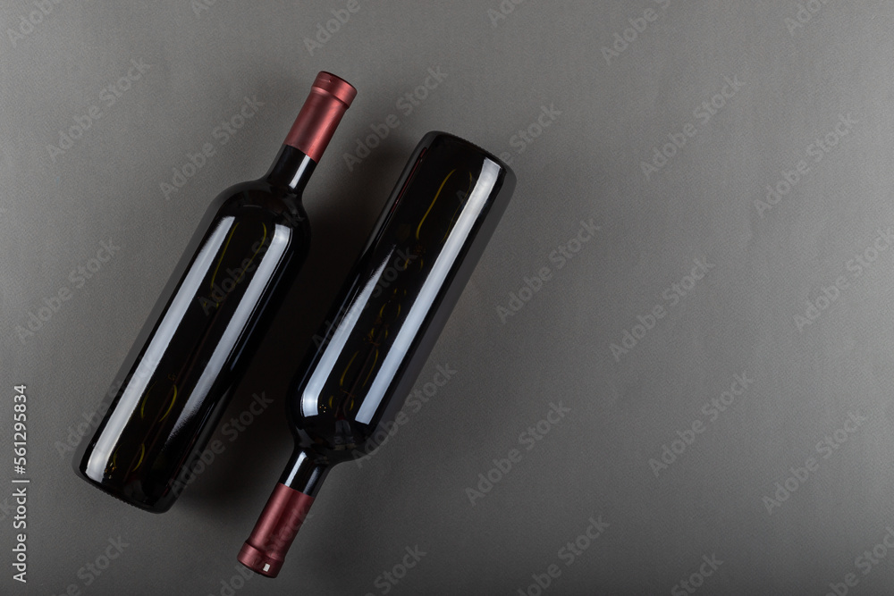 Naklejka premium A corked two bottle of red wine on a gray office. Alcoholic drink. Winemaking concept. Space for text.