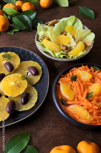 Orange salads with different ingredients. Three fruit salads on a table.