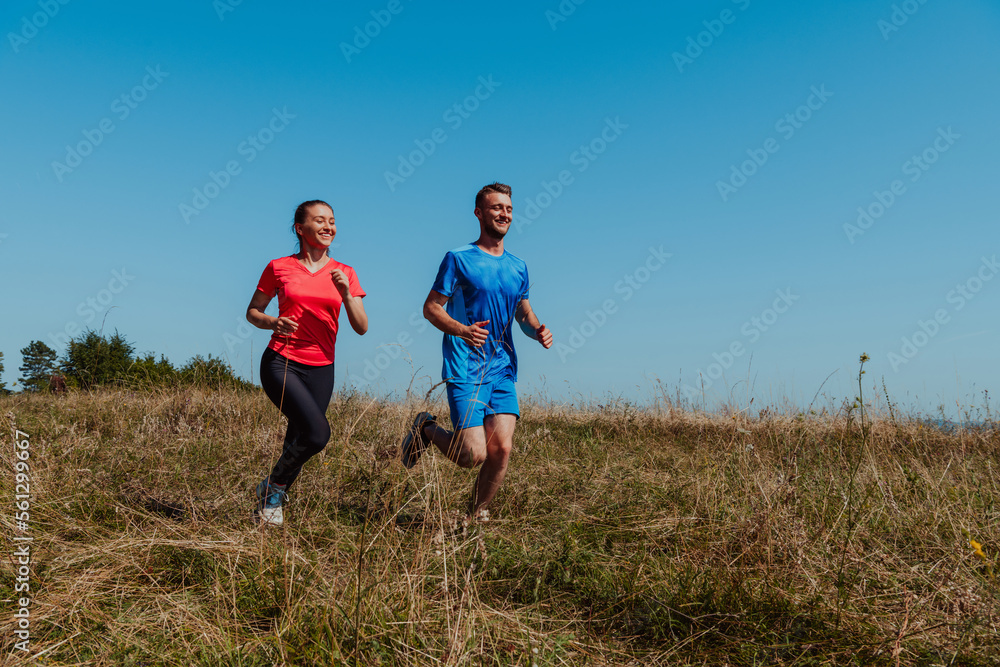 Couple enjoying in a healthy lifestyle while jogging on a country road through the beautiful sunny forest, exercise and fitness concept Couple enjoying in a healthy lifestyle while jogging on a country road through the beautiful sunny forest, exercise and fitness concept