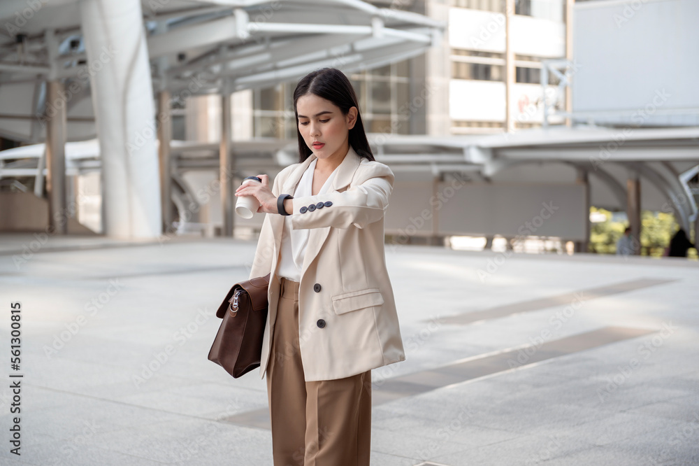 Young beautiful businesswoman in a hurry, checking time and running in modern city