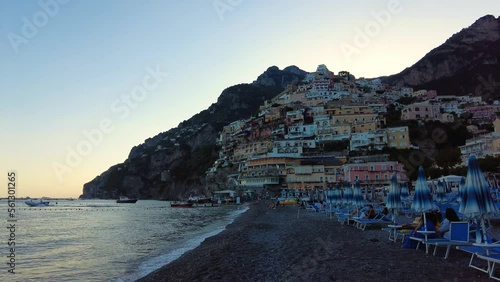 Aerial view of the famous tourist resort of the Amalfi coast. Old town with big large mountains on the background. People sitting nearby the beach. People swimming, blue transparent water. Postitano photo