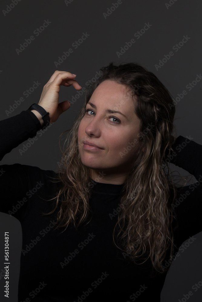 a woman with curly hair on a dark background is joyful, women over 30 years old showing happy emotions, a portrait of a joyful face in dark clothes a woman with curly hair on a dark background is joyful, women over 30 years old showing happy emotions, a portrait of a joyful face in dark clothes