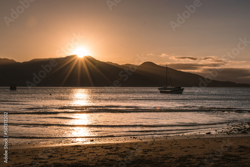 Sol se pondo atrás das montanhas iluminando o mar photo